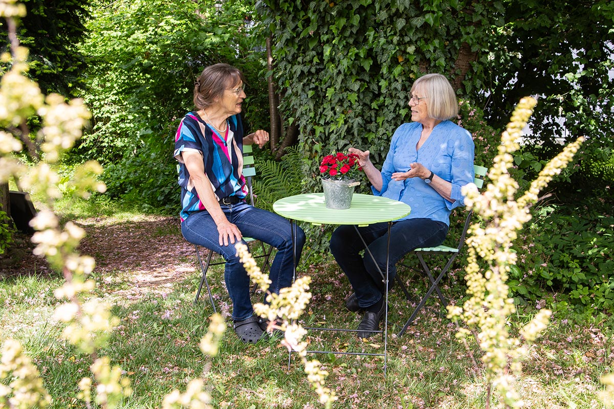 Zwei Frauen im Gespräch am Gartentisch